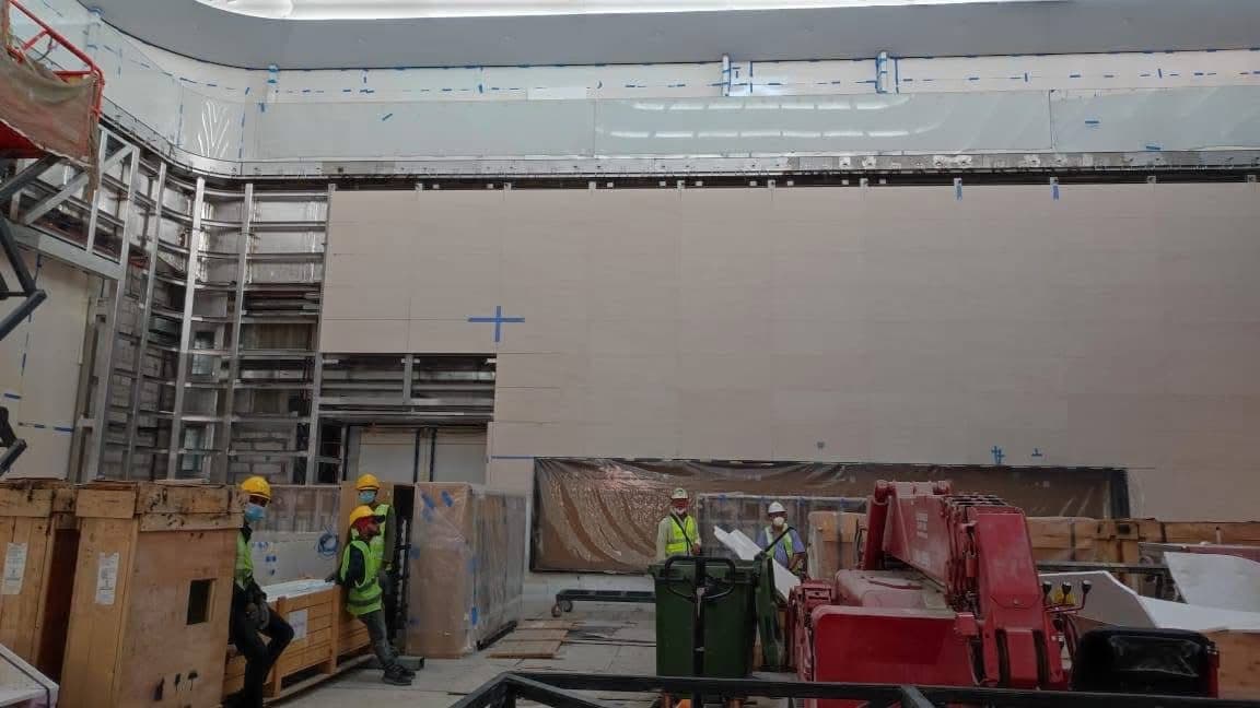 Workers and lifting equipment installing stone panels on the forum wall
