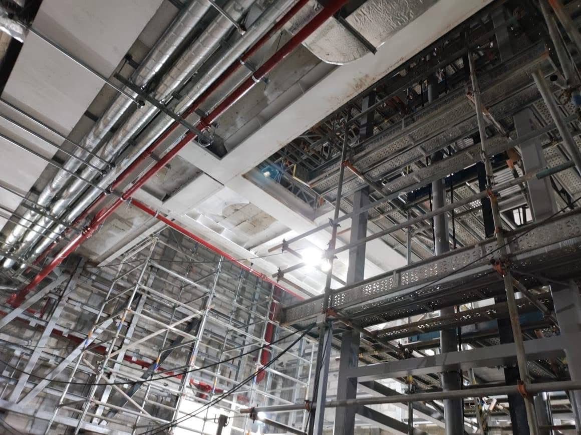 Mechanical ductwork, pipes and steel framing above full-height scaffolding