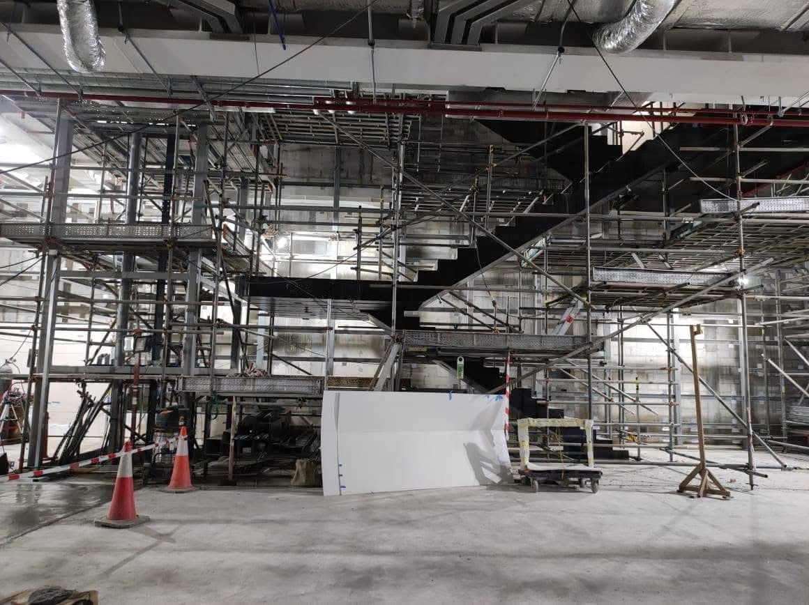 Steel stringers of the feature stair supported inside dense scaffolding