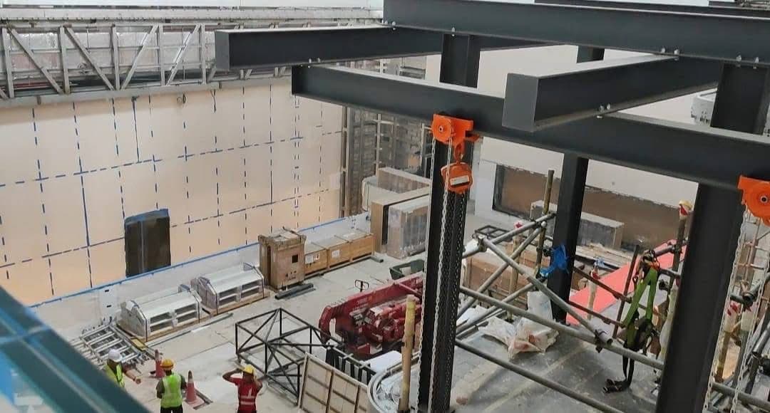 Primary steel beams and orange temporary supports over the lower-level works